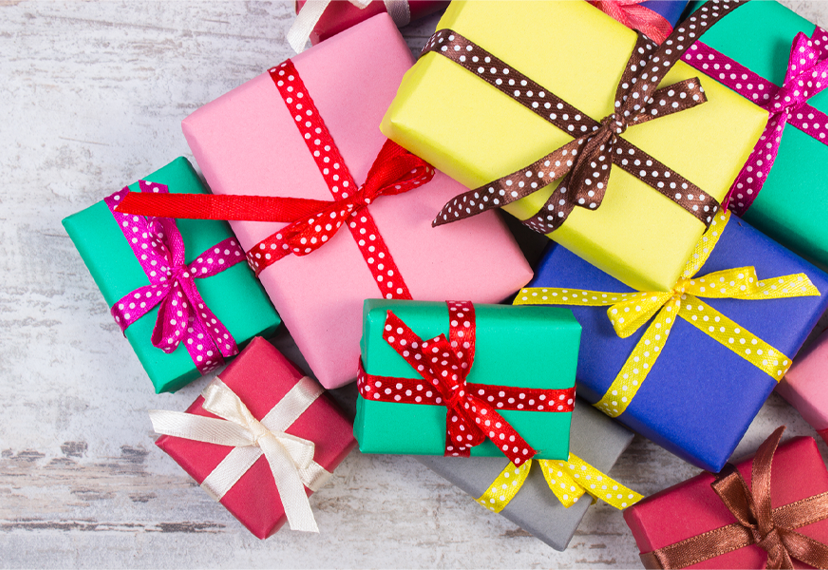 a group of multi colored wrapped presents with ribbons and bows. The background is light gray.