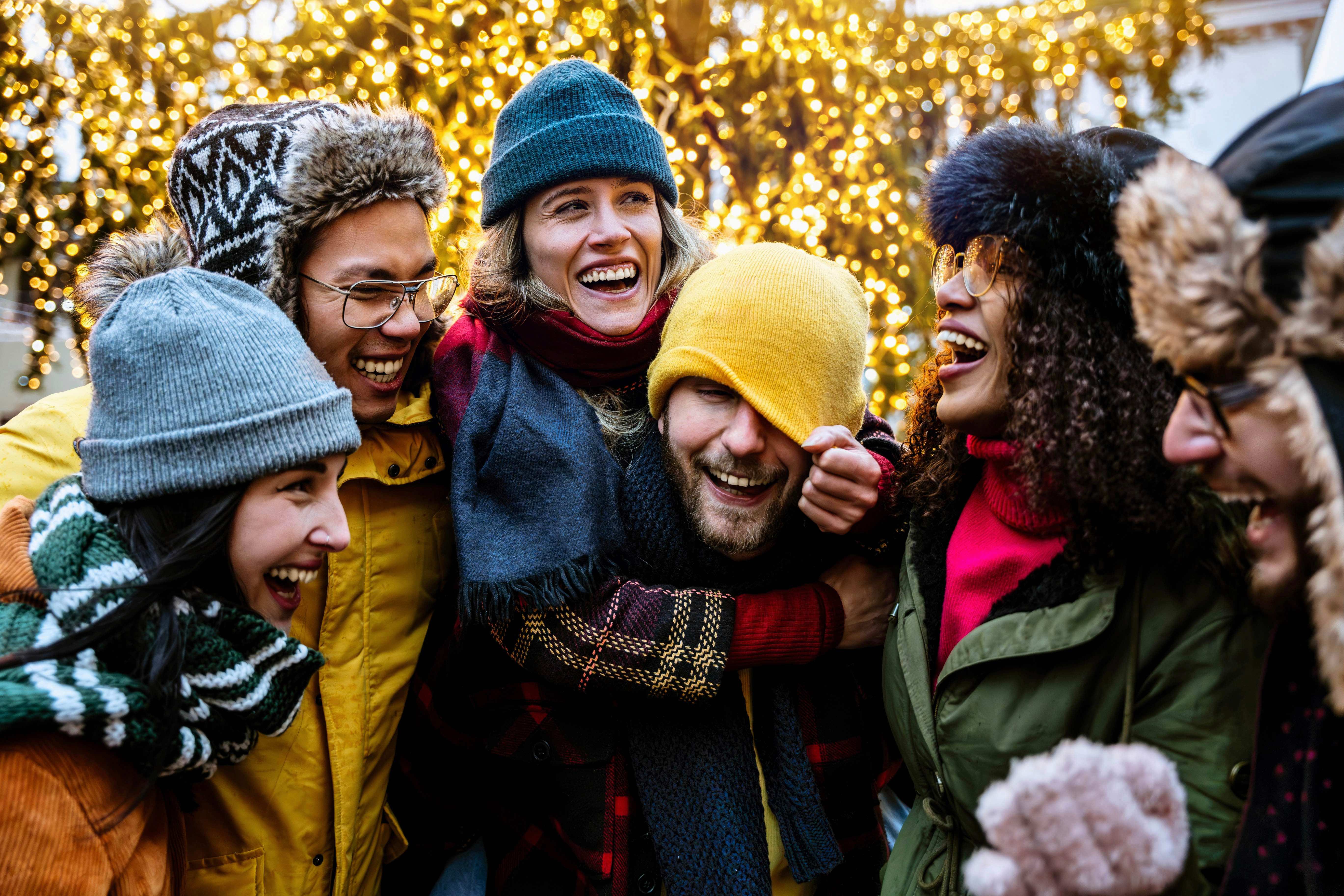 A diverse group of six people in winter clothes enjoying each others company.