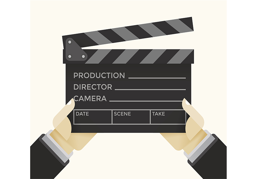 Two hands with black sleeves and a grey undersleeve hold a director's clapboard that is black and gray.