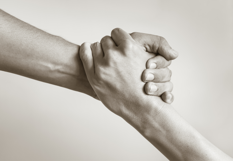 A photograph of two hands interlocked.