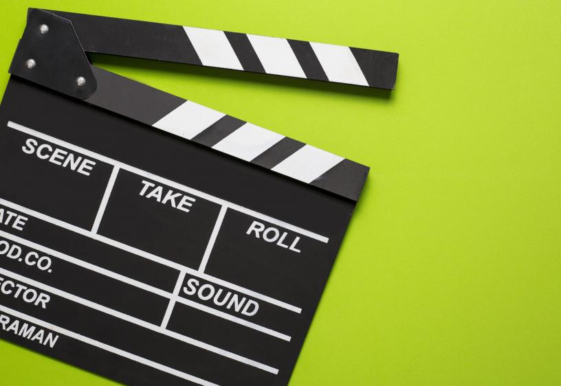 A black film clapper board is over a lime green background.