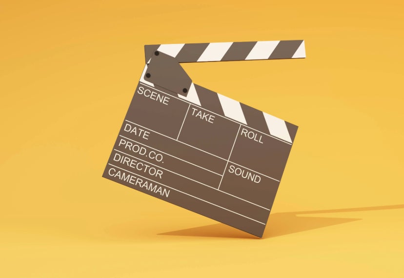 A picture of a film clapper in the middle with a golden yellow background.