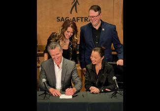 Photo of California Governor Gavin Newsom signing bill next to SAG-AFTRA President Fran Drescher