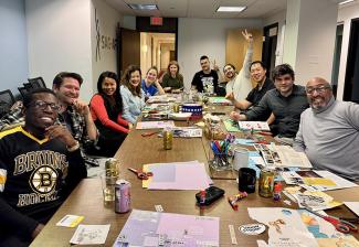  A diverse group of eleven SAG-AFTRA members pose for a photo while sitting around a table in the SAG-AFTRA New England Local conference room. 