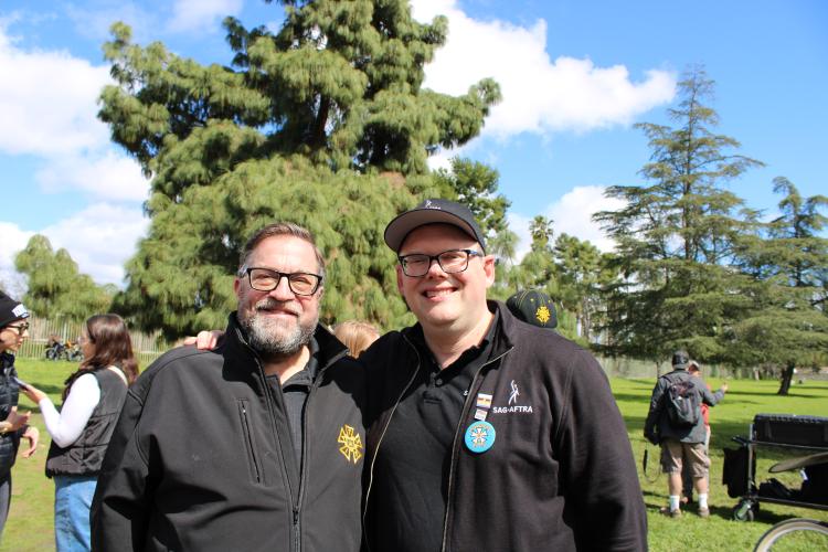 Loeb and Crabtree-Ireland stand closely for a photo. Loeb has a salt-and-pepper beard. Both men wear all-black clothing, with Loeb in a zipped hoodie with the IATSE logo.