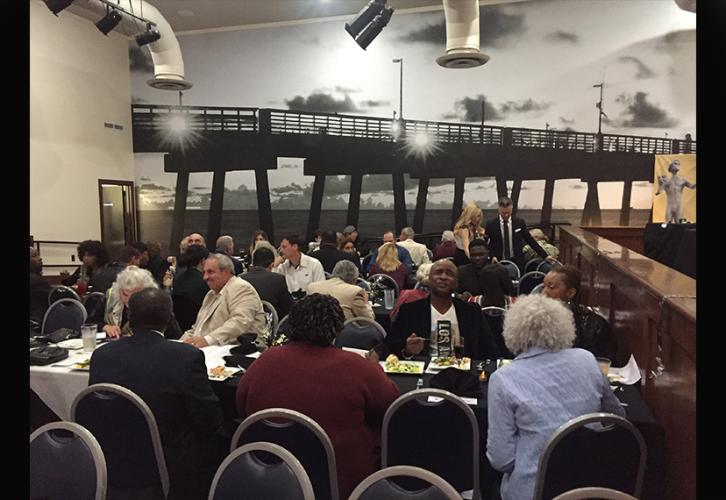 A diverse group of men and women, seated at tables.