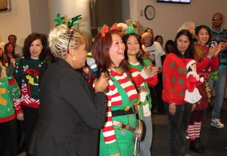 A group of individuals stand in line in ugly holiday sweaters. 