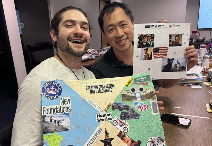 Two members proudly showcase their vision boards while sitting next to each other at the conference table; materials in the background can be seen strewn across the table, including scrap paper, glue, scissors and magazine clippings.