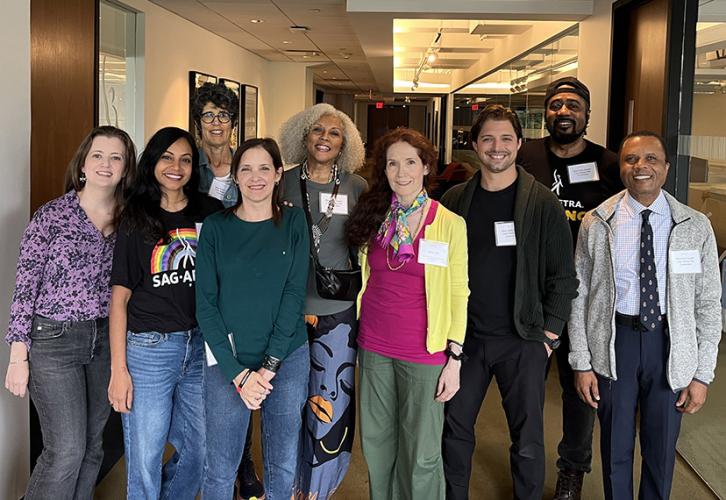 A group of people stand together in a hallway smiling at the camera.