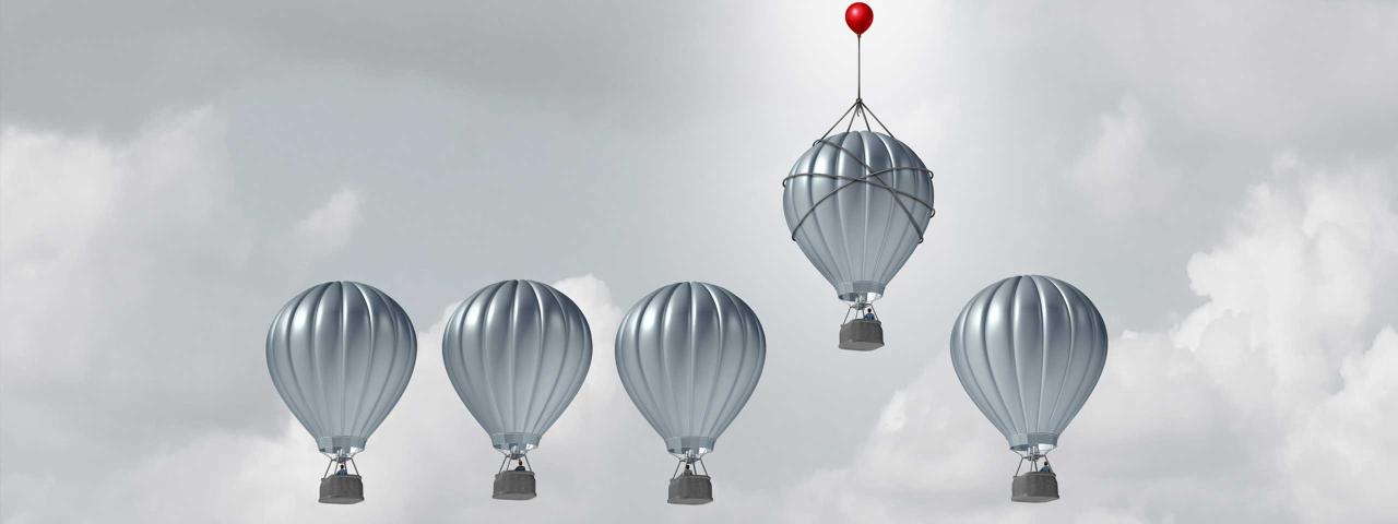 5 hot air balloons in a row with the fourth balloon from the left slightly higher than the others. Higher balloon lead by small red balloon