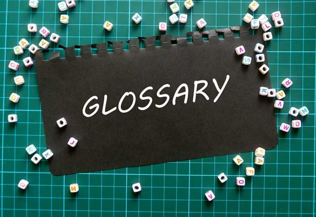 'GLOSSARY' in white text on black matte paper on a green cutting board