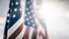 American flag draped from a pole w/ other American flags blurred in the background