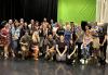 A large group of people dressed casually pose for a group photo in a studio