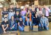 A group of individuals huddle together in a warehouse with boxes around them.