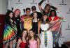 A group of individuals dressed up in Halloween costumes pose in front of a white step-and-repeat banner with SAG-AFTRA logo’s (black figure and its upraised right arm with “SAG-AFTRA” underneath) repeated on the white background.