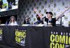 Burch, Woodward, Dalal and Elmaleh sit at a table with San Diego Comic Con-branded tablecloths. Elmaleh leans forward in her seat with her arms spread wide as the others look on. 