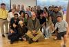 A diverse group of people sit, stand, and kneel for a group photo after the acting class with instructor Bates Wilder.