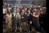 A large group of diverse people stand for a group photo in a theater.